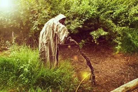A grim reaper / ghost / witch in a long hood  in the middle of the woods Stock Photos