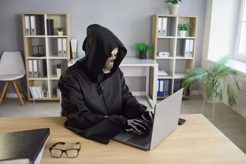 Grim Reaper Using Laptop For Online Activity In Office Foto stock