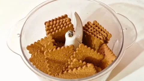 Grinding biscuits into fine crumbs using an electric food processor for desserts Stock Footage 326633360