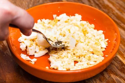 Grinding the boiled eggs for stuffing by fork Stock Photos