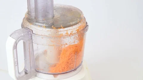 Grinding carrots in a food processor on white Stock Footage 82615228