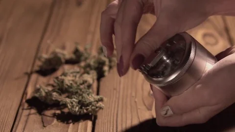 Grinding cones of marijuana with a grinder close-up. Weed buds and grinder in 스톡 동영상 83050387