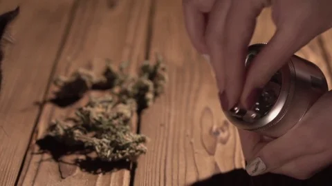 Grinding cones of marijuana with a grinder close-up. Weed buds and grinder in 스톡 동영상 83050445