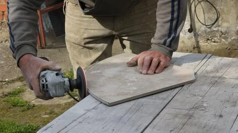 Grinding the edge of a tile with a sander Stock Photos