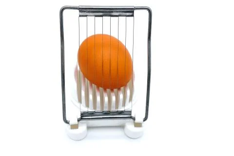 Grinding eggs for cooking. Egg in shell and cutter. White background, isolate Foto stock