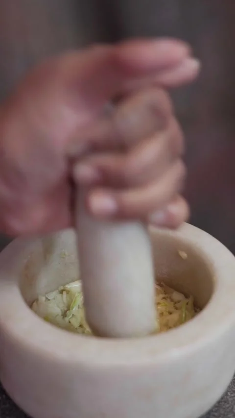 Grinding  garlic paste on Stone Mortar, making garlic paste in stone mortar. Stock Footage 283362379
