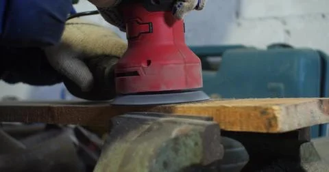 The grinding machine processes the board. A man's hand holds a sander and turns Stock Photos