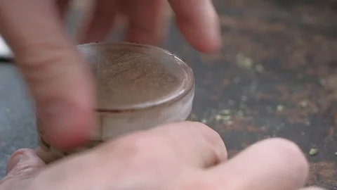 Grinding marijuana in an old grinder near the bud of medical cannabis on a rusty Stock Footage 126202201
