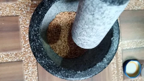 Grinding roasted rice powder in a stone mortar for Thai cooking 스톡 동영상 343591534