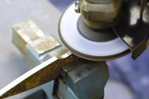 Grinding throwing knife in a vise using an angle grinder. Stock Photos