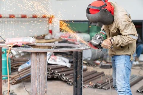 Grinding tool used by the worker produced lots of sparks. Stock Photos
