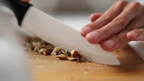 Grinding walnut kernels with a kitchen knife on a cutting board. Close-up of Stock Footage 213316861
