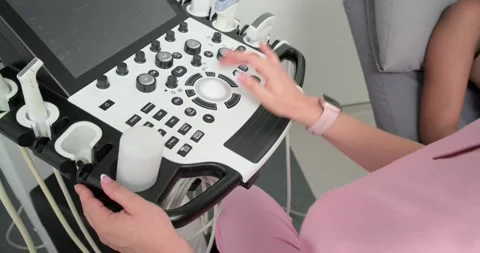 Gripping handle, tech is turning trackball, tuning knobs, lifting probe to set Stock Footage 335514361