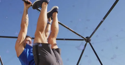 Gripping pull-up bar, man performing hanging leg raises at outdoor gym for core Stock Footage 331615113
