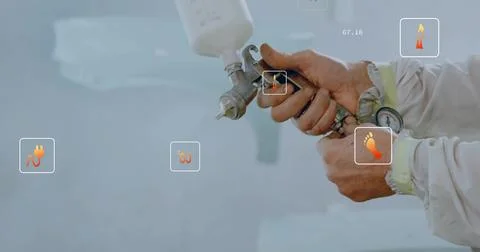 Gripping tech operating spray gun, white cup, UI icons at paint bay, wearing Stock Photos