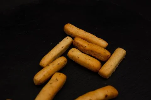 Grissini lying on a plate on a black background Stock Photos