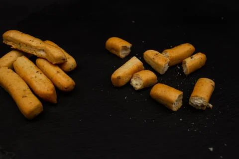 Grissini lying on a plate on a black background Stock Photos