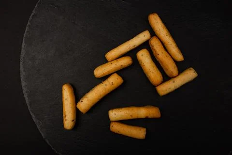 Grissini lying on a plate on a black background Stock Photos