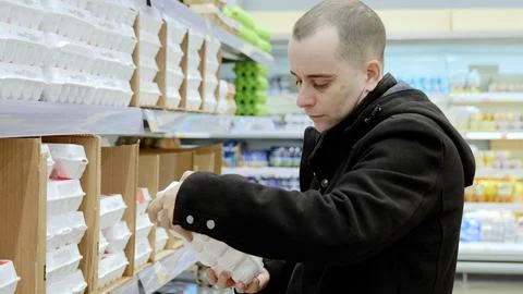 Grocery shopper checking egg package quality, ensuring freshness and selecting Stock Photos
