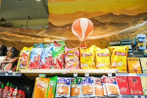Grocery store display with various packaged asian snack food on shelf under Stock Photos