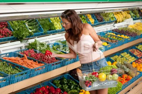 Grocery store shopping - young woman buying vegetable Stock Photos
