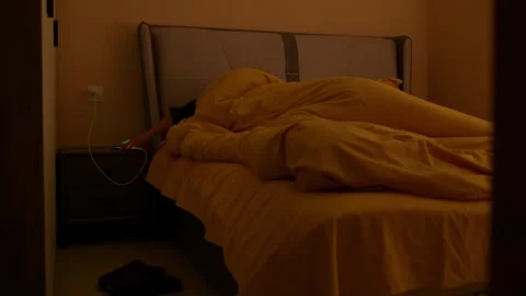 A groggy guy drags himself out of bed after his alarm goes off. Stock Footage 330835611
