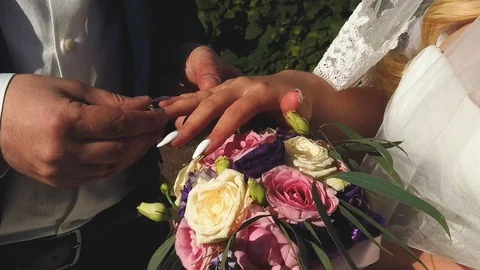 Groom and bride put on wedding rings to each other on summer park background Stock Footage 124960201