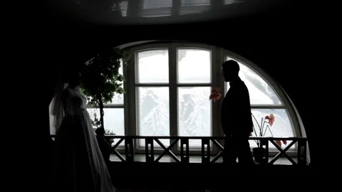 The groom and the bride stand at the window. Silhouettes of people. Black and wh Vidéo 73636199
