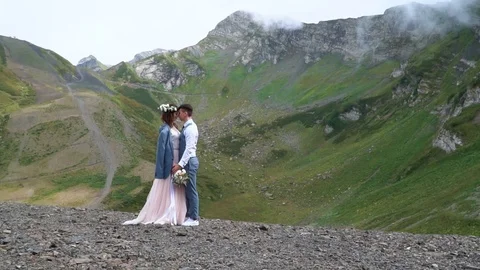 Groom and bride standing in the front of distant marvelous green mountain peaks Vidéo 101977478