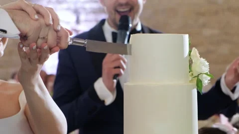 Groom and bride with their hands together hold a silver knife cut a wedding cake Stock Footage 243679982