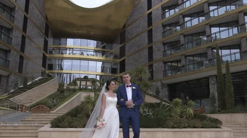 Groom and bride walking down the stairs on the luxury hotel territory near pool Stock Footage 94216771
