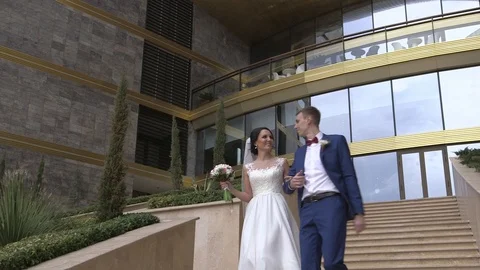 Groom and bride walking down the stairs on the luxury hotel territory Video stock 94216845