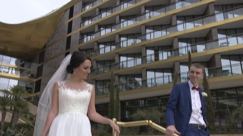 Groom and bride walking down the stairs on the luxury hotel territory Stock Footage 94217606