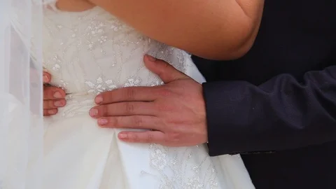 The groom in a black suit hugs the bride's waist in a white dress Stockbeeldmateriaal 123700910