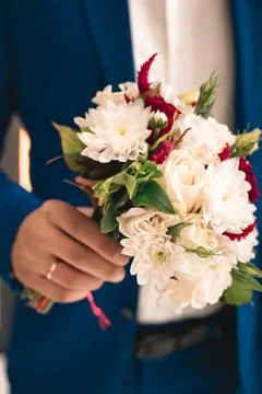 Groom in a blue suit holds a wedding bouquet Stock Photos