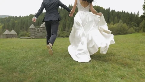 Groom with bride running. View from behind. Wedding couple. Newlyweds Stock Footage 122653262