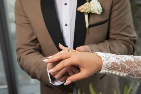The groom in a brown jacket puts the ring on the bride's finger.Wedding cerem Stock Photos