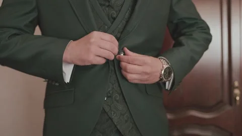 Groom buttoning dark green suit jacket with watch on wedding day Stock Footage 337195135