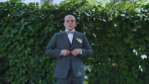 The groom is buttoning his jacket on the street Stock Footage 222355112