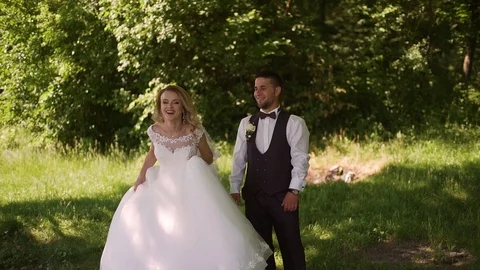 Groom comes to charming blonde bride with bouquet behind her. Slow motion Stock Footage 107776853