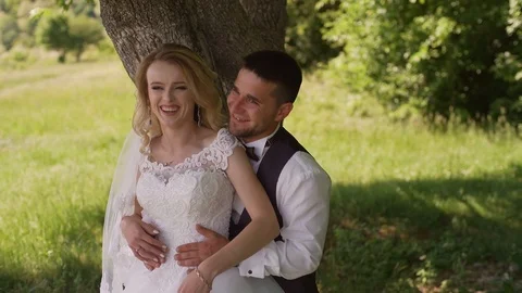 Groom comes to charming blonde bride with bouquet behind her. Slow motion Stock Footage 107779839