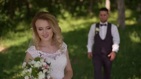 Groom comes to charming blonde bride with bouquet behind her. Slow motion Stock Footage 107780481
