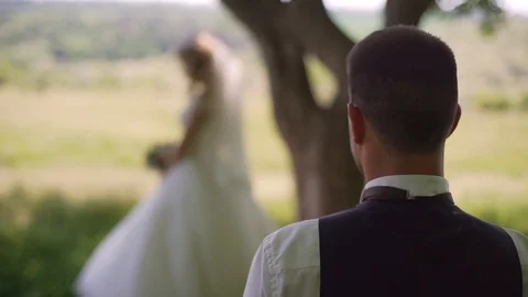 Groom comes to charming blonde bride with bouquet behind her. Slow motion Stock Footage 107781334