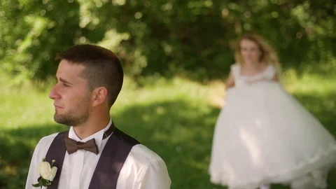 Groom comes to charming blonde bride with bouquet behind her. Slow motion Stock Footage 107783483