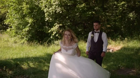 Groom comes to charming blonde bride with bouquet behind her. Slow motion Stock Footage 107784807