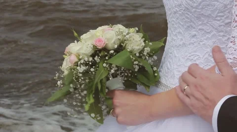 Groom embraces the bride stroking the arm near the sea. Wedding day Stock Footage 65386863