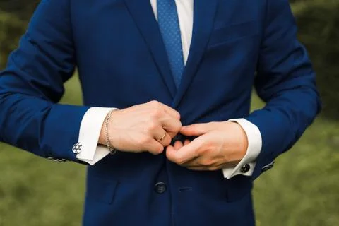 The groom fastens a button on a blue jacket, close-up Stock Photos