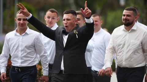 Groom flexing and having fun walking with groomsmen on wedding day. Happy classy Stock Footage 201154528