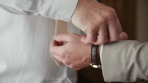 A groom gets ready for his wedding day, as he adjusts his tie and watch Stock Footage 345643160