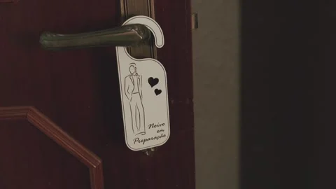 Groom getting ready door hanger sign on wooden door handle Vidéo 337194410